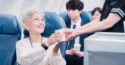 Asian older woman getting served drink in flight