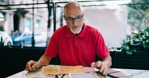 Bald man wearing glasses and looking at papers on the table