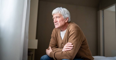 Senior man sits staring blankly out window