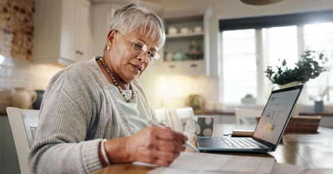 senior woman doing paperwork with laptop