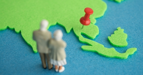 Old couple figurine looking at map with red pin 