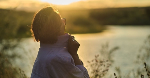 Retiree woman overlooking a river at sunset